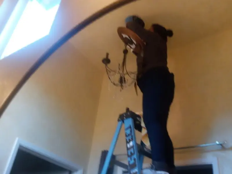 Electrician installing a chandelier in a Huber Heights residence